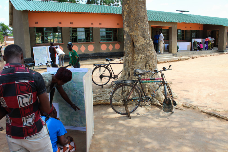 Community members gather around high-resolution satellite maps and registries displaying their village's land claims, produced by the Chipata District Land Alliance with support from USAID.