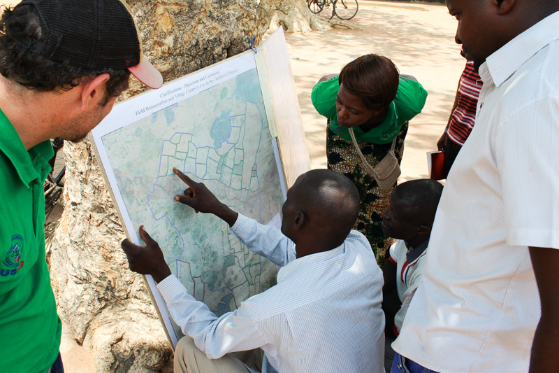 Precious Zulu (Chipata District Land Alliance) and Matt Sommerville (USAID) explore a map of land ownership in Kalichero, Zambia with local stakeholders.
